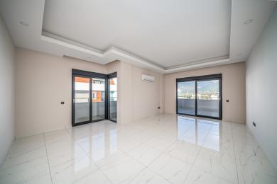 Bright, empty Alanya room featuring marble floors, recessed lighting, and balcony access via black-framed sliding glass doors.