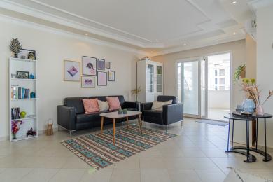 Az Alanya apartman nappalija fekete bőrkanapéval, mintás szőnyeggel és világos, szellős légkörrel rendelkezik.