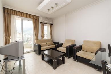 Alanya onroerend goed woonkamer met toegang tot het balkon, met neutraal getinte zitplaatsen, donkere houten accenten en een heldere, luchtige sfeer.