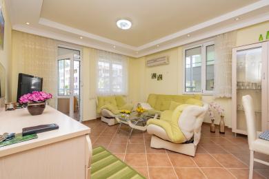Alanya woning woonkamer met tegelvloeren, gele muren, comfortabele zitplaatsen en helder, natuurlijk licht dat een gezellige sfeer creëert.