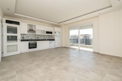 Alanya'da beyaz dolapları, mozaik backsplash'i, fayans zemini ve balkon erişimi olan, aydınlık ve modern bir alan yaratan mutfak.
