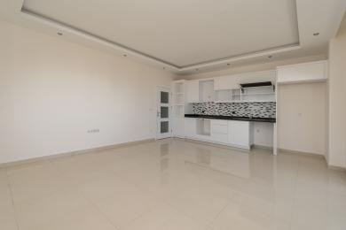 Lyst kjøkken i en Alanya-leilighet med hvite skap, svarte benkeplater, mønstret backsplash og blanke fliser.