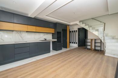 Alanya ejendomskøkken med elegante grå skabe, trædetaljer, marmor bagplade og lyst, moderne design.