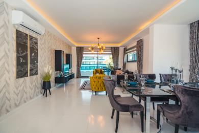 Alanya Immobilie: Heller, offener Wohn- und Essbereich mit modernen Möbeln, Zugang zum Balkon und warmer Umgebungsbeleuchtung.
