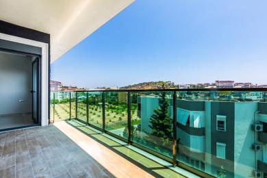 Alanya ejendom balkon med glasrækværk, flisegulv og lyse, solrige udsigter.