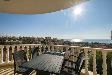 Alanya woning balkon met wicker meubilair biedt een prachtig uitzicht op zee onder een heldere, zonnige hemel.