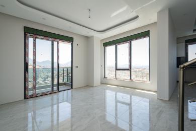 Šviesi, erdvi svetainė Alanya nuosavybėje su marmurinėmis grindimis, dideliais langais ir išėjimu į balkoną su vaizdu į miestą.
