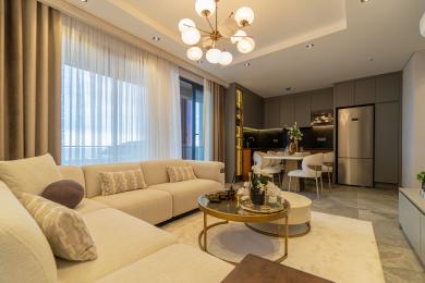 Alanya property: Bright, open-plan living room with modern kitchen, neutral tones and stylish globe chandelier.