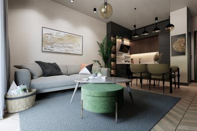 Alanya property living room with a modern kitchen, featuring a grey sofa, green ottoman, and warm, inviting lighting.