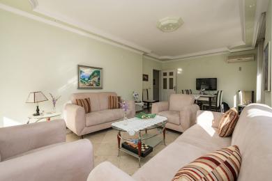 Alanya Immobilie Wohnzimmer mit plüschigen rosa Sofas, Marmorböden und heller, natürlicher Beleuchtung, die eine komfortable Atmosphäre schafft.