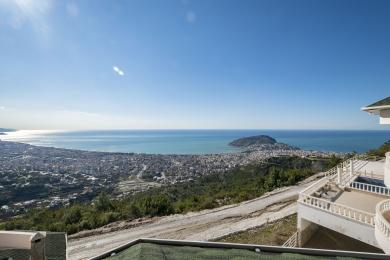 Balkon nekretnine u Alanji sa zadivljujućim panoramskim pogledom na grad i Sredozemno more, okupan jarkim suncem.