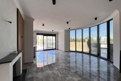 Mermer zeminli, kavisli pencereli ve modern aydınlatmalı, ferah bir atmosfer yaratan aydınlık Alanya oturma odası.
