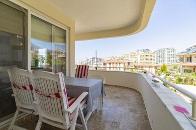 Balcon al proprietății din Alanya cu podea de marmură, set de luat masa în aer liber și vedere asupra orașului în lumină naturală.