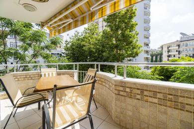 Balkon nekretnine u Alanji sa zidovima obloženim pločicama, tendom i vanjskim blagovaonskim setom, nudi svijetle i opuštajuće poglede.