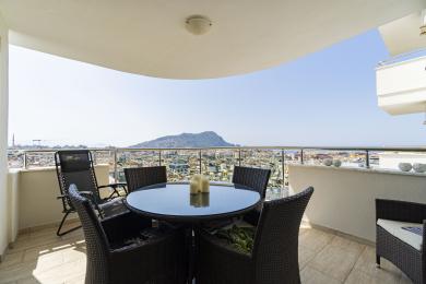 Alanya property balcony with wicker furniture and stunning city and mountain views.