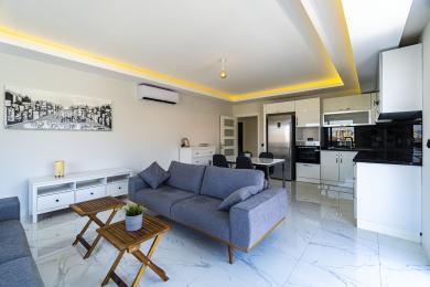 Alanya Immobilie: Heller, offener Wohnraum mit moderner Küche, Marmorböden und atmosphärischer Deckenbeleuchtung.