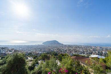 Alanya mulkining yorqin, quyoshli osmon ostida shahar, dengiz va tog 'manzarasini namoyish etadi.
