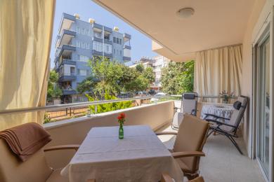 Alanya altan med bord, stole og solrig udsigt over de omkringliggende bygninger.