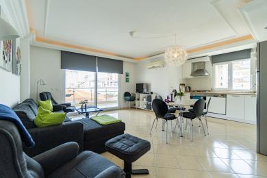 Livingul luminos și open-space al proprietății din Alanya are mobilier modern, vedere la balcon și o bucătărie albă elegantă.
