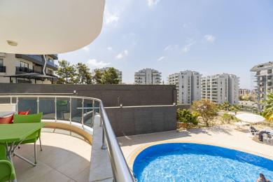 Balkon nekretnine u Alanji sa pogledom na bazen, sa jarkim dnevnim svetlom, modernim ogradama i prostorom za sedenje na otvorenom.