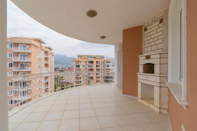 Balkon nekretnine u Alanji s podovima od pločica, vanjskim kaminom i slikovitim pogledom na grad i planine.