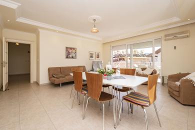 Lichte Alanya appartement woonkamer met tegelvloeren, eettafel en toegang tot het balkon, wat een comfortabele sfeer creëert.