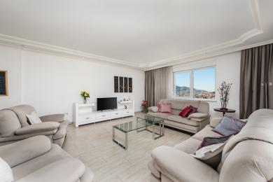 Alanya property living room with neutral sofas, tile flooring, bright natural light, and city views.