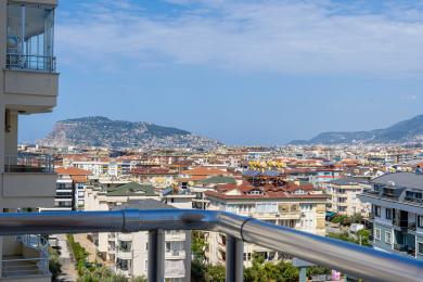Balkon med panoramaudsigt over Alanya by og bjerge, lys solrig atmosfære.