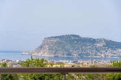 منظر لشرفة عقار في ألانيا يظهر المدينة والبحر وقلعة ألانيا تحت ضوء النهار الساطع.