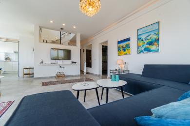 Bright, modern villa interior featuring an open-plan living area with stylish furnishings and a view of the kitchen and staircase.
