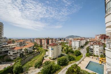 Alanya eiendom balkongutsikt som viser byens skyline, Middelhavet og en lys og solrik atmosfære.
