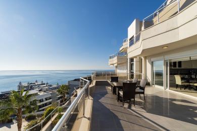 Alanya ejendom balkon med havudsigt, flisegulv, glasrækværk og udendørs spisesæt i skarpt sollys.