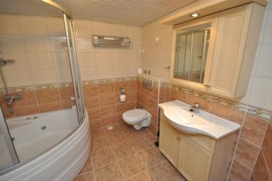 Alanya fastighet badrum med jacuzzi, kaklade väggar och ljus träkommod med förvaring.