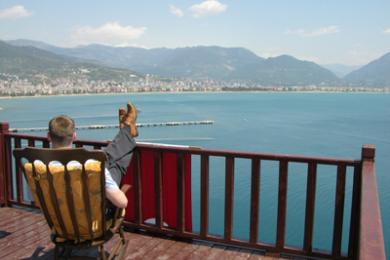 Alanya property balcony with wooden deck, railing, and stunning sea and mountain views.