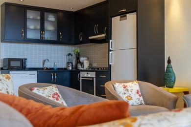 Alanya ingatlan konyhája sötét szekrényekkel, csempézett hátfallal, modern berendezésekkel és kényelmes, virágos párnákkal.