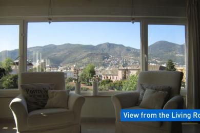 Livingul luminos din Alanya are fotolii confortabile și o vedere panoramică a munților de la fereastră.