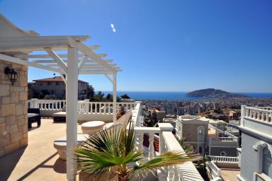 Alanya feriebolig balkonudsigt: Middelhavet, byens skyline og en solrig, afslappet atmosfære.