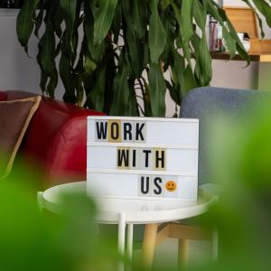 Σύγχρονος επαγγελματικός χώρος στην Αλάνια με πινακίδα "Εργαστείτε Μαζί Μας", που προωθεί τη συνεργασία και την ανάπτυξη.