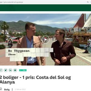 Alanya, Tyrkiet: To mænd går langs havnen med bjerge og en båd i baggrunden.